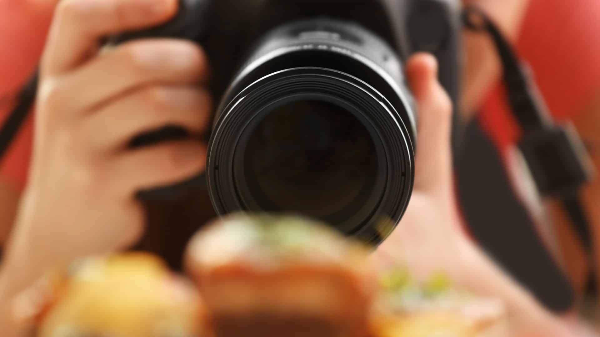 Close-up of a photographer taking pictures of gourmet food, capturing high-quality visuals for use in food marketing and promotional campaigns.