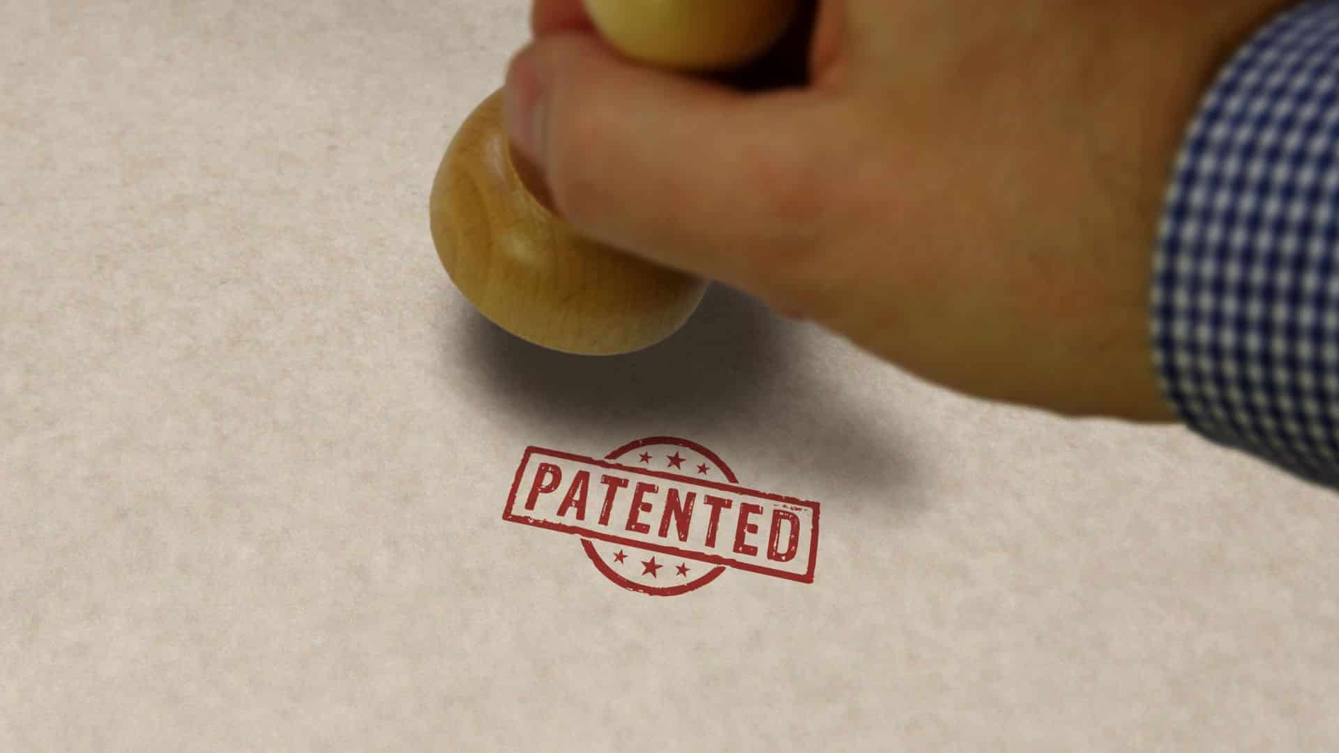 Close-up of a hand stamping the word "PATENTED" on paper, representing intellectual property protection and patents in the food and beverage industry.