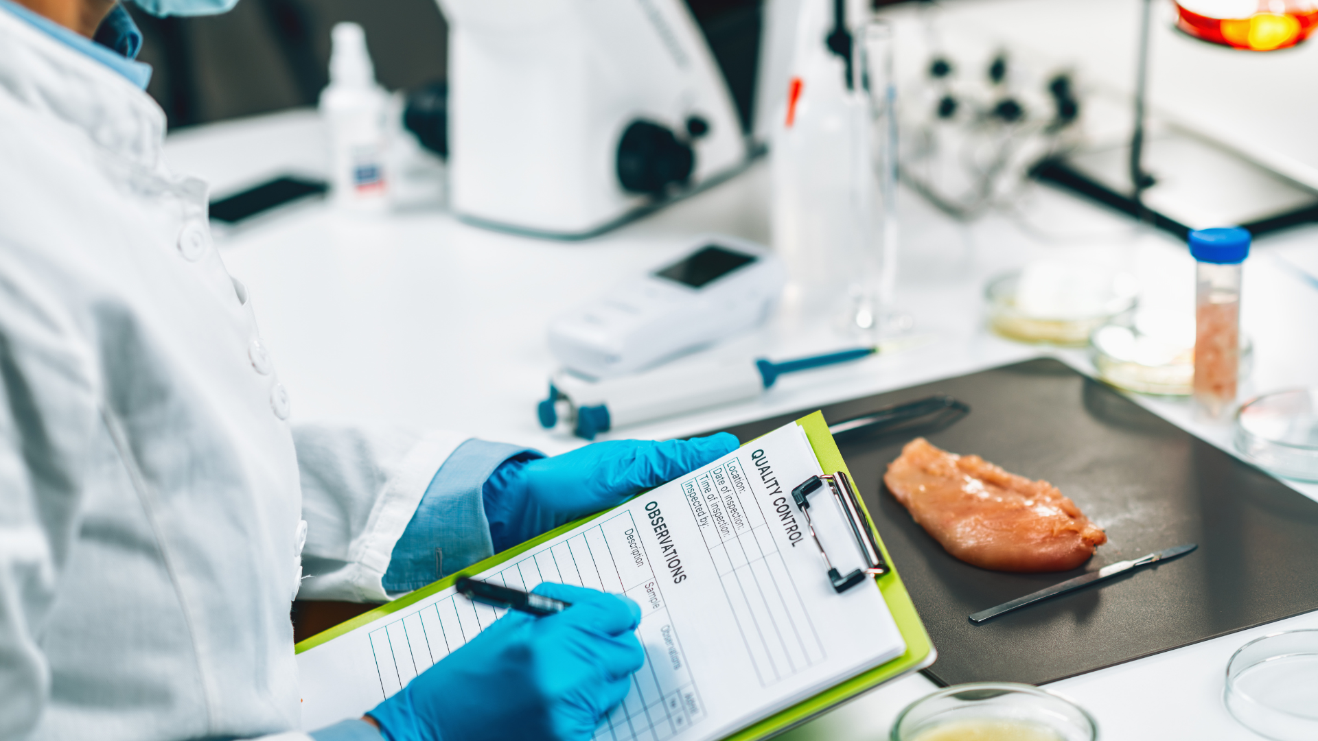 Food safety manager inspecting raw chicken in a laboratory setting, wearing protective gloves and recording quality control observations on a clipboard.
