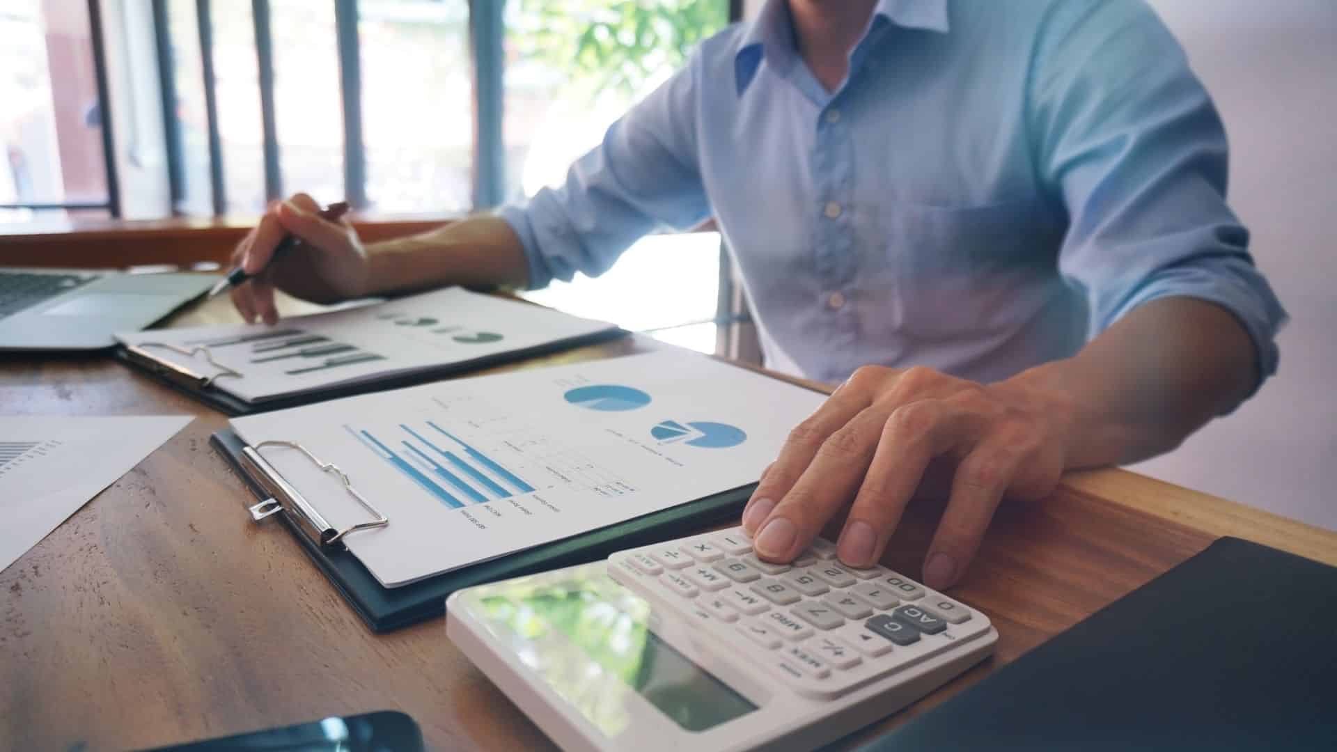 Person analyzing financial charts and using a calculator, representing a food policy analyst evaluating food systems data to influence public policy decisions.
