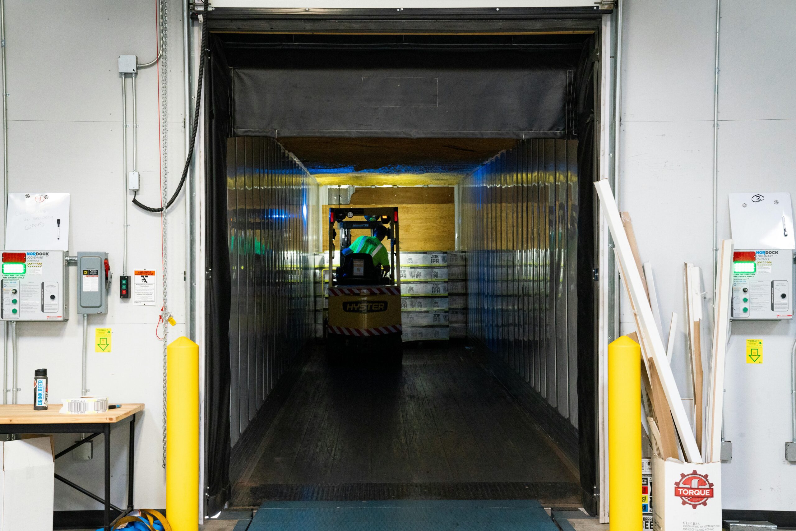 A man operating a forklift and loading a skid into a truck