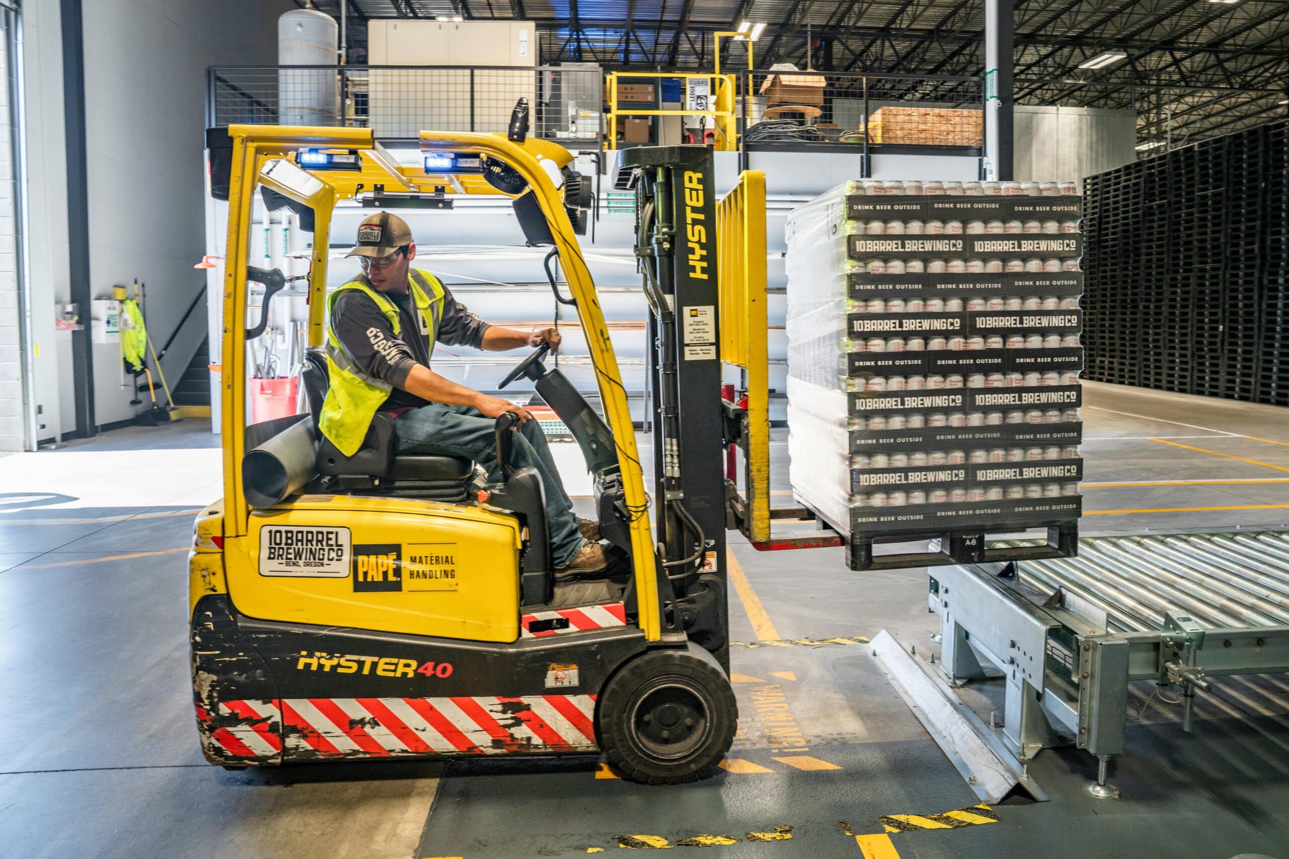A man operating a forklift and putting beer on a skid