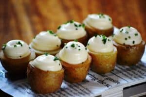 Potatoes on White Newspaper Near Brown Wooden Surface with sour cream