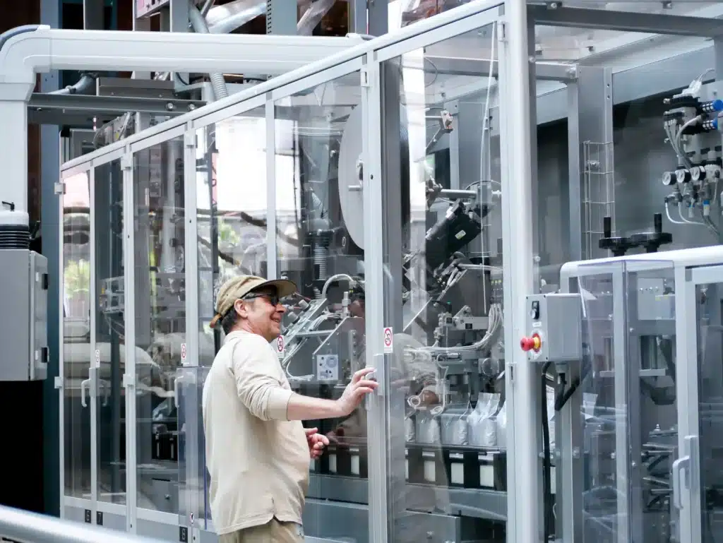 Food manufacturing jobs worker operating industrial machinery behind glass