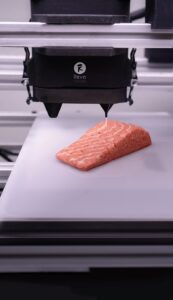 This image displays a plant-based, 3D printed salmon filet alternative based on mycoprotein, produced by the Austrian company Revo Foods. This product was the first 3D printed product available in food retail (2023). This image is related to 3D Food Printing, Meat Alternatives and Food Technology.