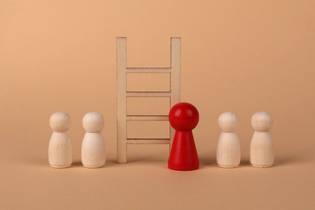 Abstract representation of leadership with wooden figures and ladder on a neutral background.